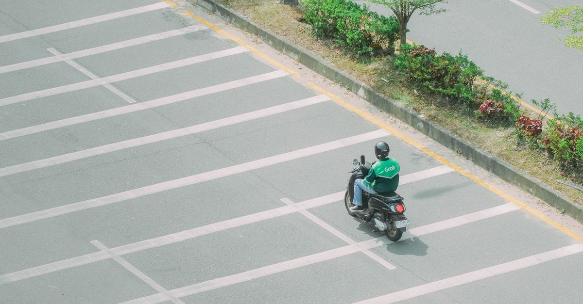 A Grab motorbike rider on a quiet street captured from above, symbolizing urban mobility.